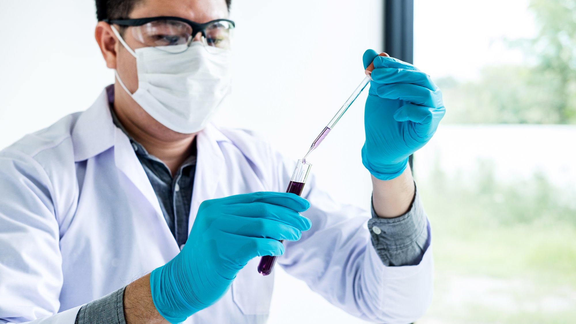 Biochemistry laboratory research, Scientist or medical in lab coat holding test tube with reagent with drop of color liquid o