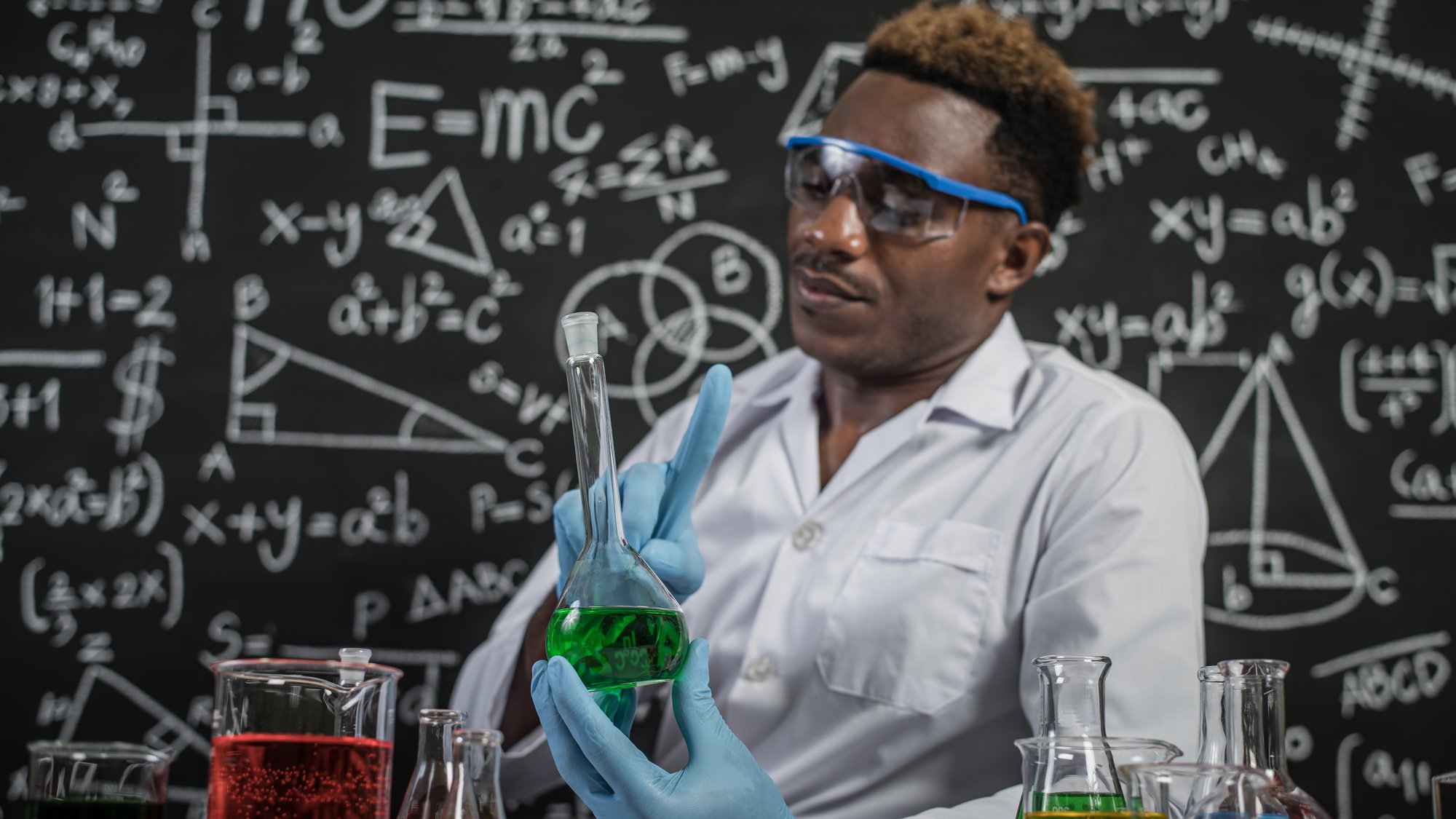 Scientists use the idea and hold the beaker with green chemicals in the laboratory.