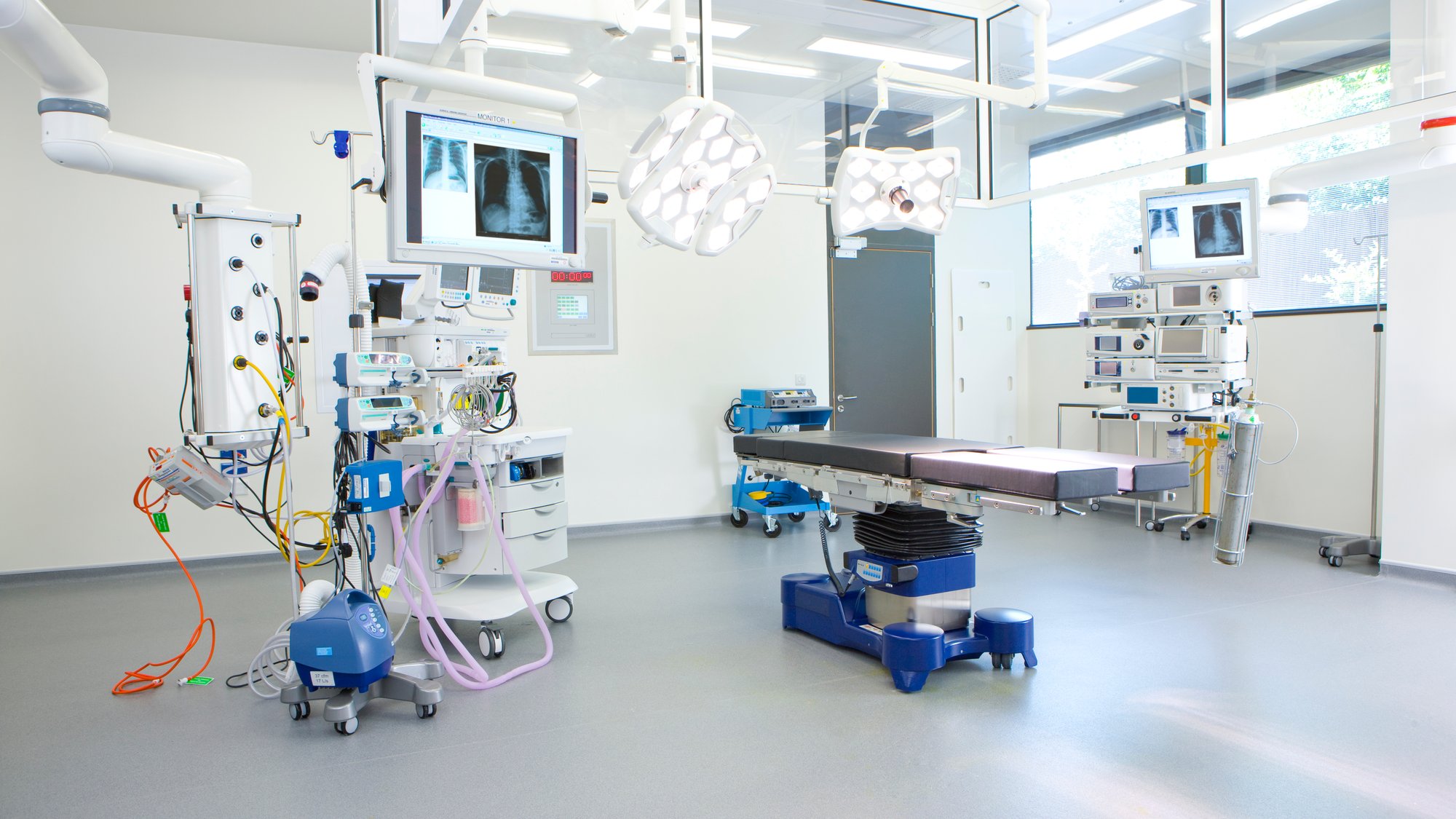 A wide angle view of a well lit operating room equipped with latest machinery and medical equipment